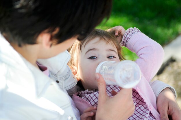 Bebé niña bebiendo leche de la botella de bebé. Madre alimentando a hija de la botella.
