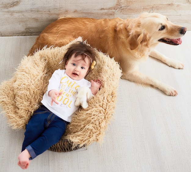 Foto gratuita el bebé pequeño miente en la cesta cerca del perro