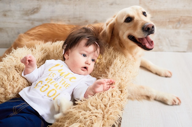 El bebé pequeño miente en la cesta cerca del perro