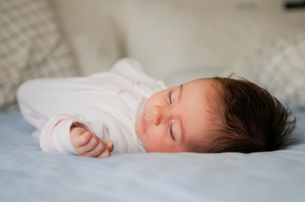 Bebé recién nacido durmiendo en hojas azules en casa