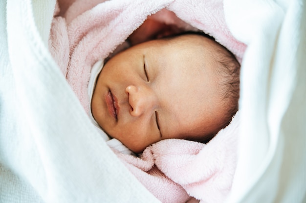 Bebé recién nacido durmiendo en una manta rosa suave