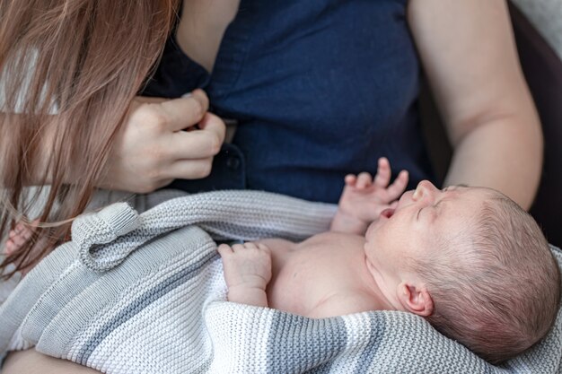 El bebé recién nacido está llorando, la joven madre está amamantando al bebé.