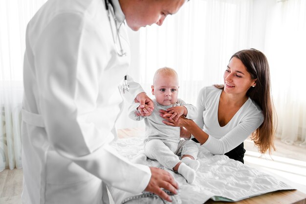 Bebé recién nacido sostenido por el médico y la madre.