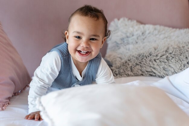 Bebé sonriente gateando en la cama