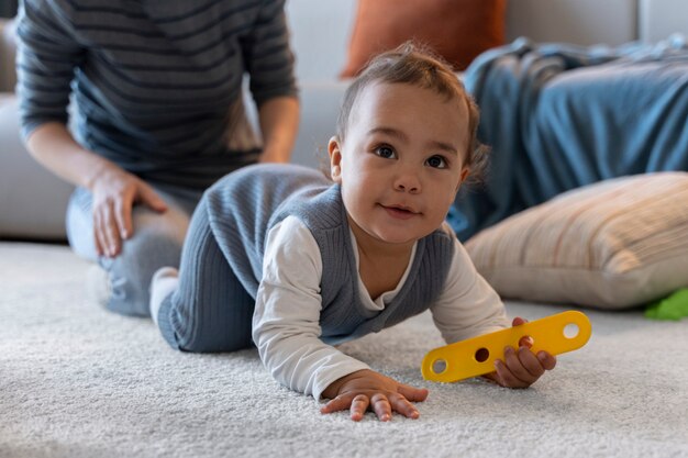 Bebé sonriente gateando con un juguete en la mano