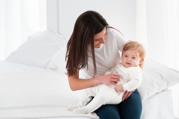 Bebé sonriente retenido por la madre