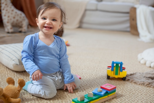 Foto gratuita bebé sonriente de tiro completo en el piso