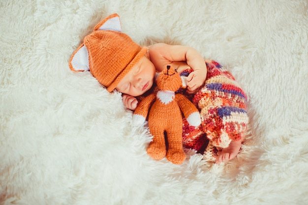 Foto gratuita bebé sostiene pequeño juguete de zorro durmiendo en la almohada blanca