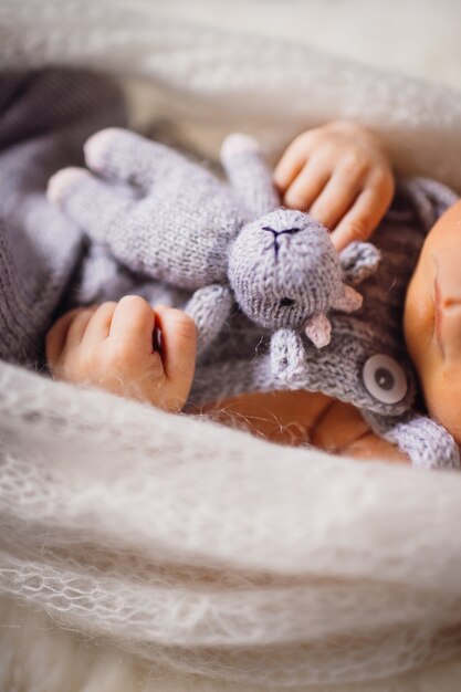 El bebé sostiene la vaca de juguete que miente en la almohada mullida