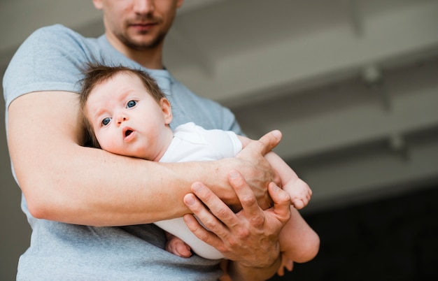 Bebé tendido en manos del padre