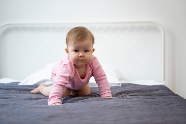 Foto gratuita bebé de tiro completo gateando en la cama