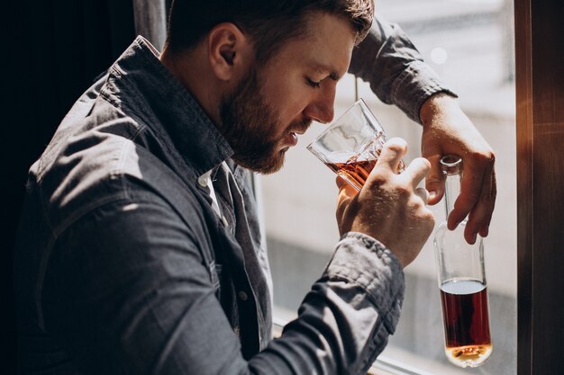 Bebedero hombre deprimido con botella de whisky