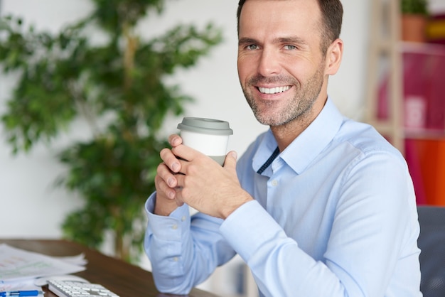 Beber café sonriendo mientras se toma un descanso