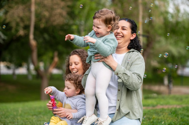 Bebés sonrientes al aire libre en el parque con madres lgbt