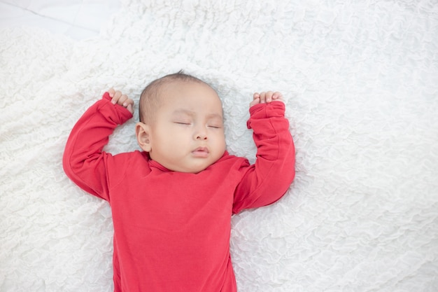 Bebés vestidos con camisas rojas durmiendo en la cama