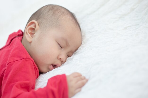 Bebés vestidos con camisas rojas durmiendo en la cama