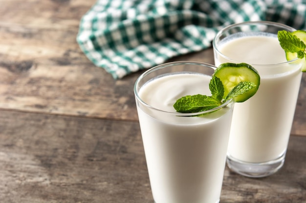 Bebida ayran con menta y pepino en vaso sobre mesa de madera