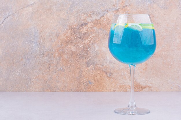 Bebida azul con rodajas de limón sobre superficie blanca