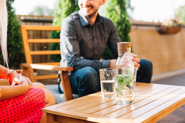 Bebida a base de hierbas en la mesa de madera con pareja sentada en la silla