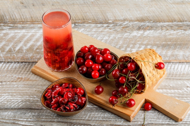 Bebida de cereza con cerezas, mermelada en una jarra de madera y tabla de cortar