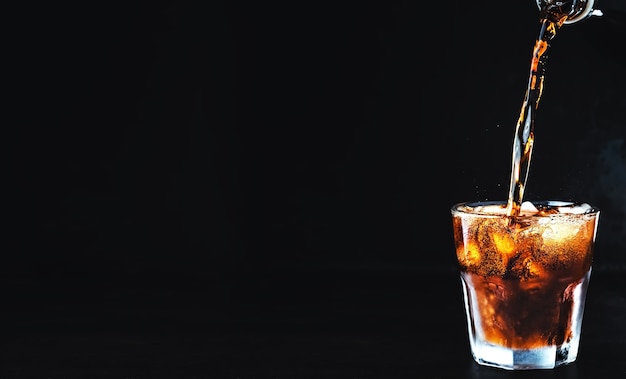 Bebida de cola carbonatada suave se vierte en un vaso de hielo