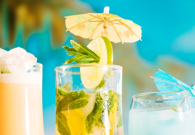Bebida fresca con rodajas de limón y menta en vidrio decorado con sombrilla.