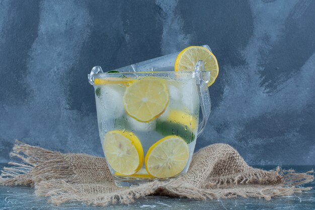 Bebida fría de limón sobre la toalla, sobre fondo azul. Foto de alta calidad