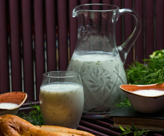 Foto gratuita bebida fría de yogurt con menta y hierbas dentro en un vaso y un frasco