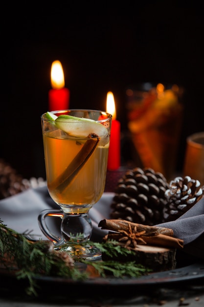 Bebida de invierno con canela y rodaja de manzana en la mesa de navidad