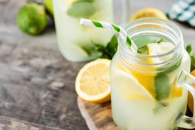 Bebida de limonada en un vaso de tarro e ingredientes en tablexA de madera