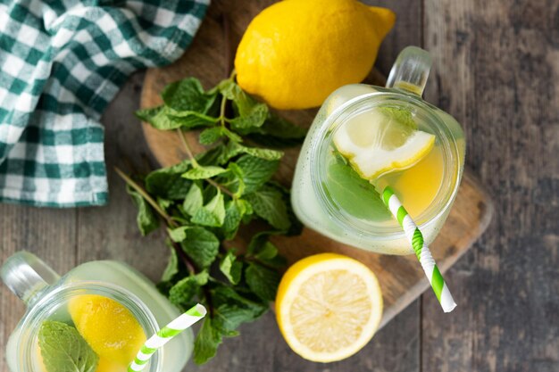 Bebida de limonada en un vaso de tarro e ingredientes en tablexA de madera