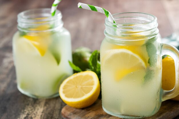 Bebida de limonada en un vaso de tarro e ingredientes en tablexA de madera