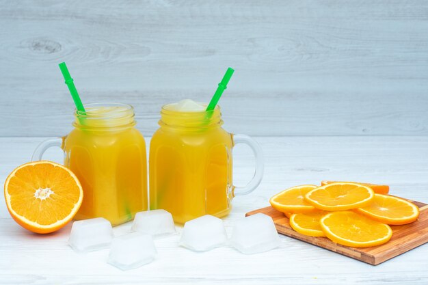 bebida de naranja con cubitos de hielo sobre superficie de madera