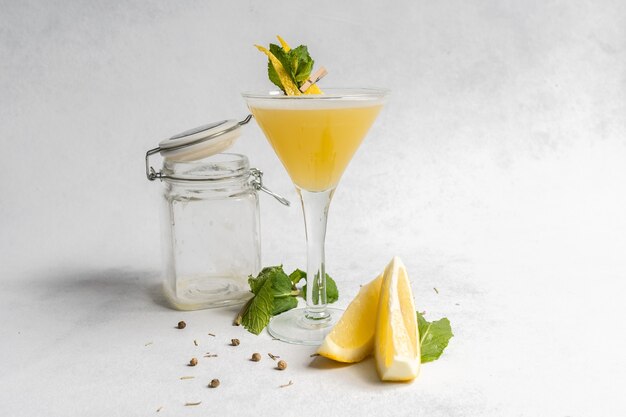 Bebida refrescante decorada con cáscara de limón y hojas de menta