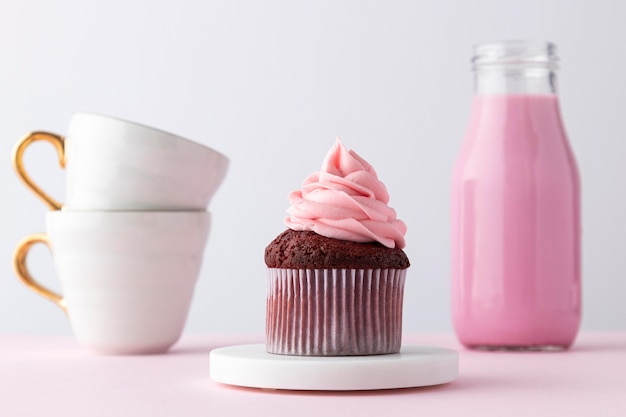 Bebida rosa, cupcake y tazas.