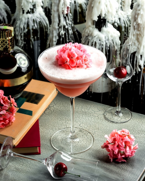 Foto gratuita bebida rosa con espuma en un vaso y flores rosadas