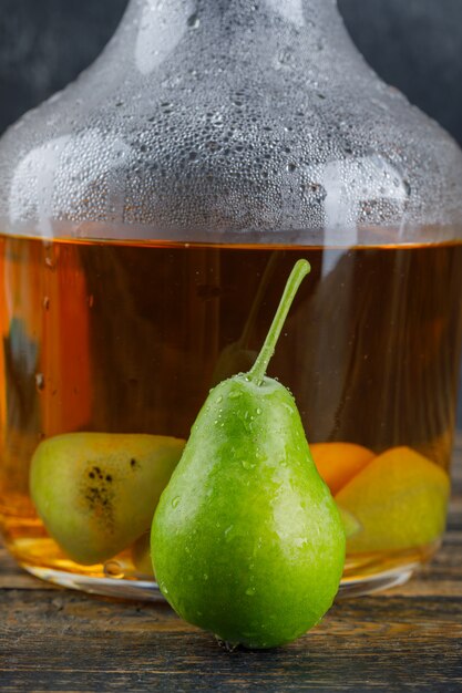 Bebida de sidra con pera en una botella en la mesa de madera