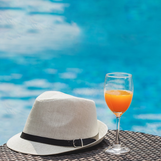 Bebida y sombrero con piscina de fondo