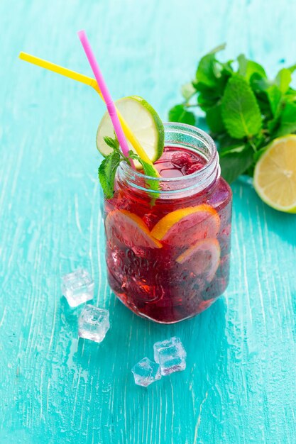 Bebida de verano con frambuesas, limón y hielo en una mesa de madera antigua