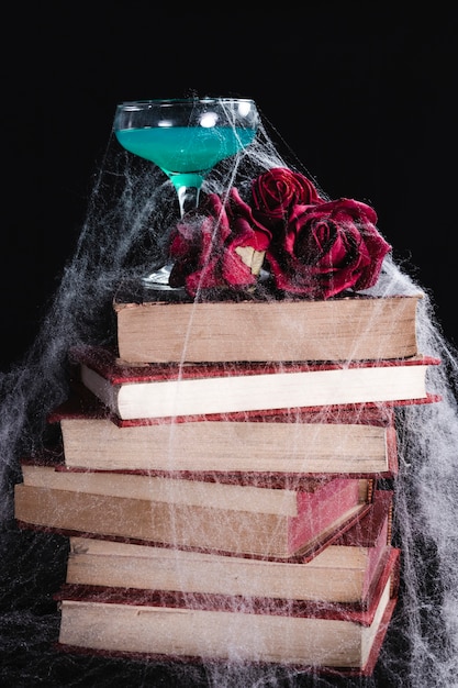 Bebida verde con rosas, libros y telaraña