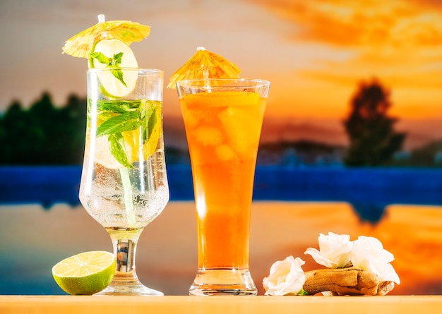 Bebidas frescas de naranja con cubitos de hielo de menta y lima en rodajas y flores blancas