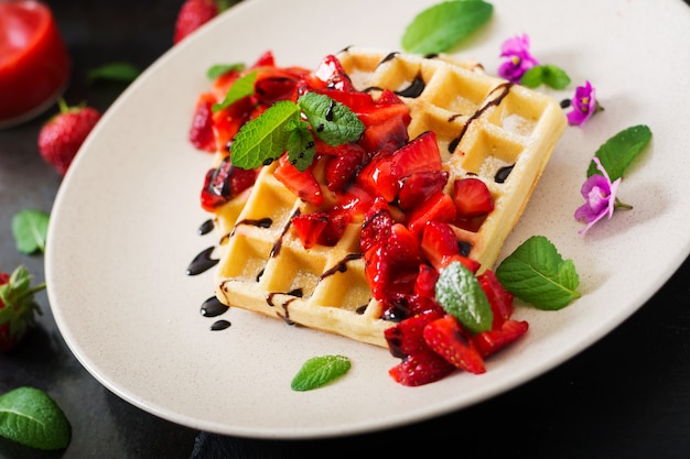 Bélgica obleas con fresas, chocolate y jarabe en un plato.