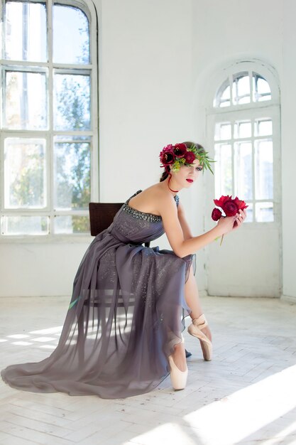 La bella bailarina sentada con un vestido largo y gris