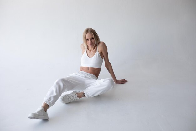 Bella chica rubia con una camiseta blanca y medias posando sobre un fondo blanco