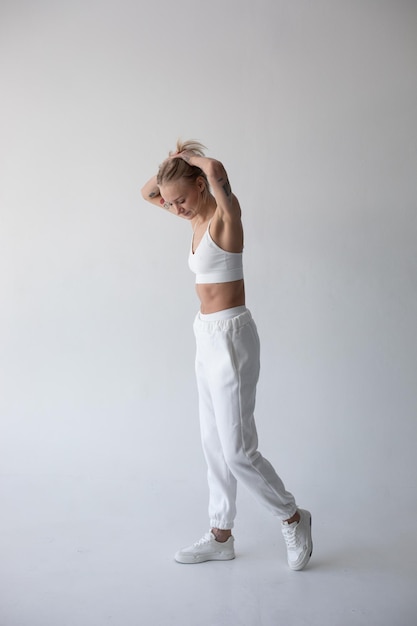 Bella chica rubia con una camiseta blanca y medias posando sobre un fondo blanco