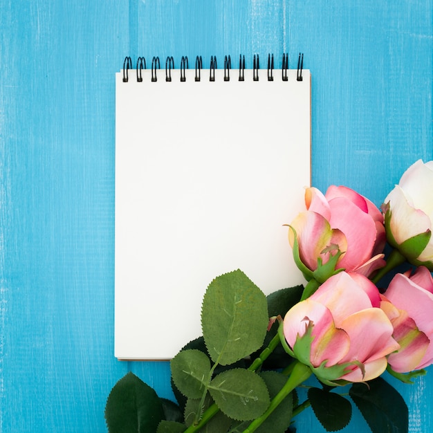 bella composición con cuaderno y rosas en madera azul