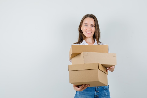 Foto gratuita bella dama en blusa blanca con cajas, vista frontal.