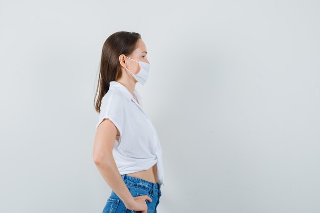 Bella dama de blusa blanca, mascarilla mirando a otro lado.