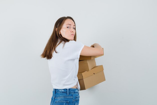 Bella dama en blusa blanca sosteniendo cajas mientras no quiere compartirlas.