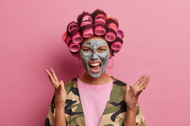 Foto gratuita bella dama con máscara para el cuidado de la cara con rizadores de pelo aislados